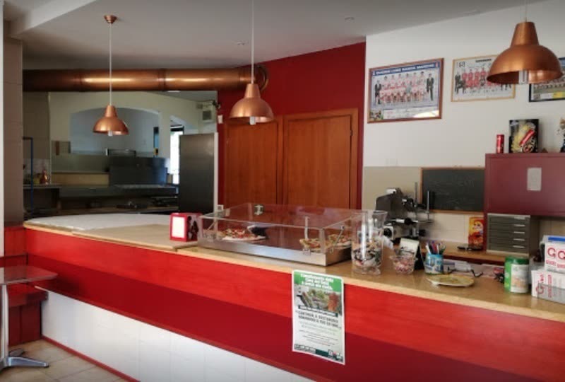 Il bancone rosso con le lampade di rame dentro la pizzeria