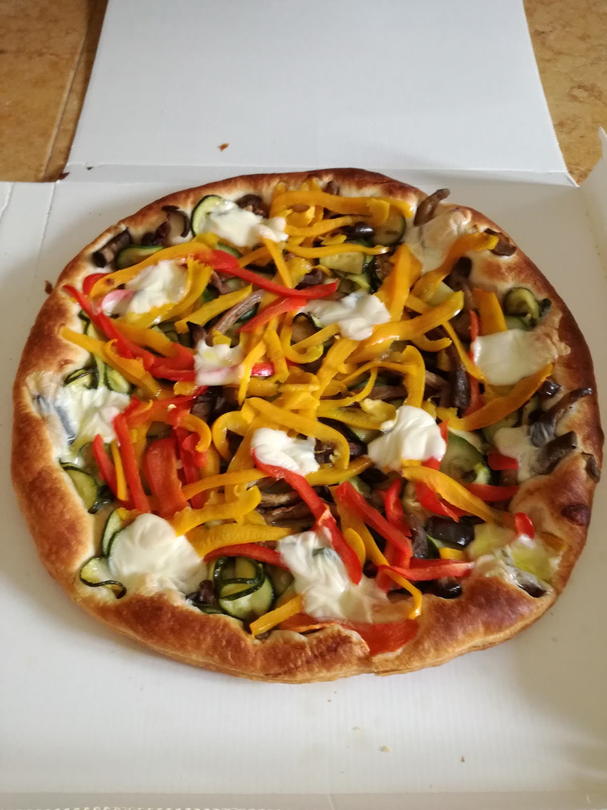 Pizza tonda con verdure grigliate e stracciatella, nel cartone da asporto